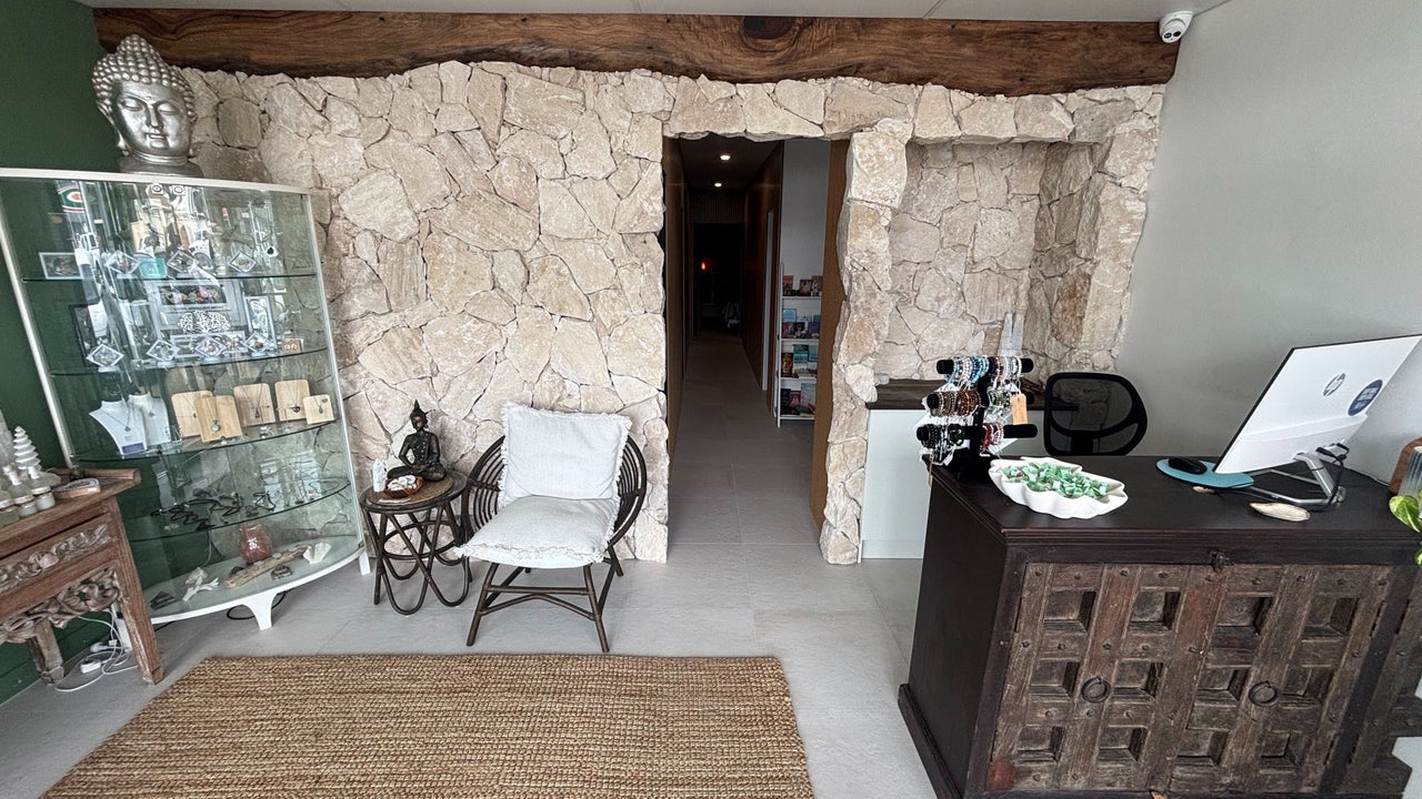 Reception at The Healing Cottage Palm Beach, with natural stone wall, Buddha, and retail nook