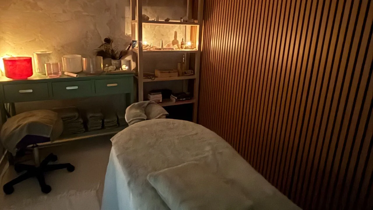 Candlelit treatment room at The Healing Cottage Palm Beach, with massage table and sound bowls